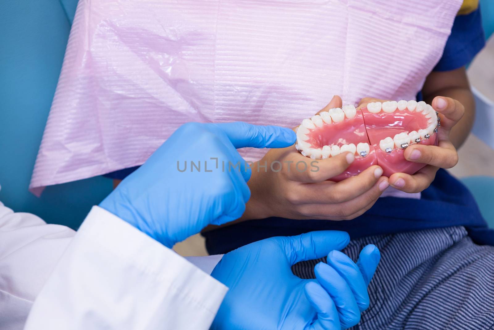 Cropped image of dentist showing dentures to boy by Wavebreakmedia