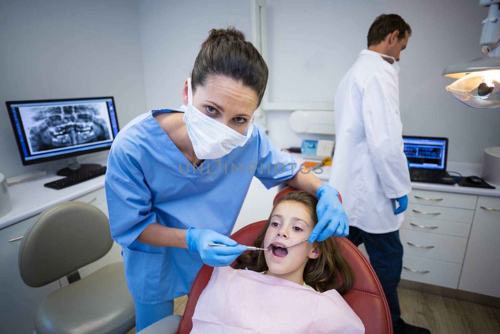 Dentist examining a young patient with tools by Wavebreakmedia