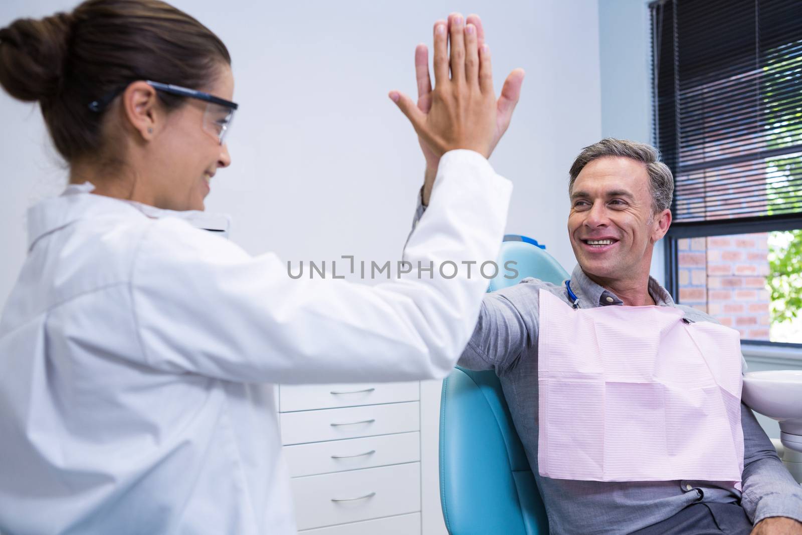  Happy dentist giving high five to man by Wavebreakmedia