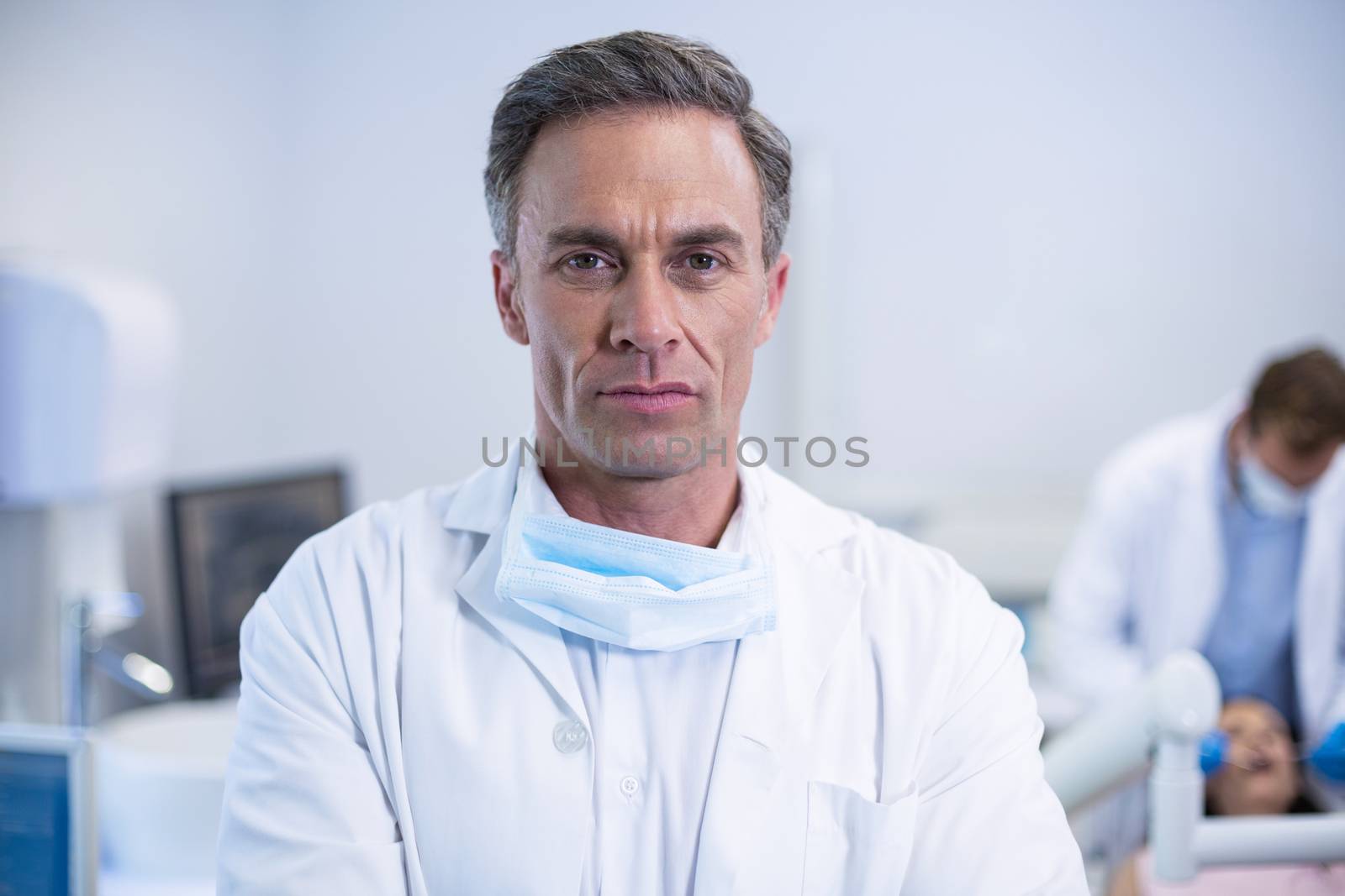 Confident dentist standing at dental clinic by Wavebreakmedia