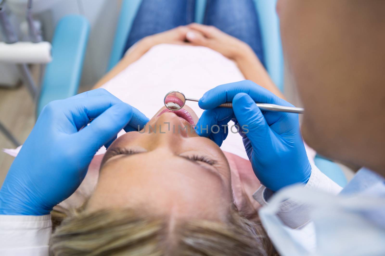 Patient lying on bed while dentist examining at clinic by Wavebreakmedia
