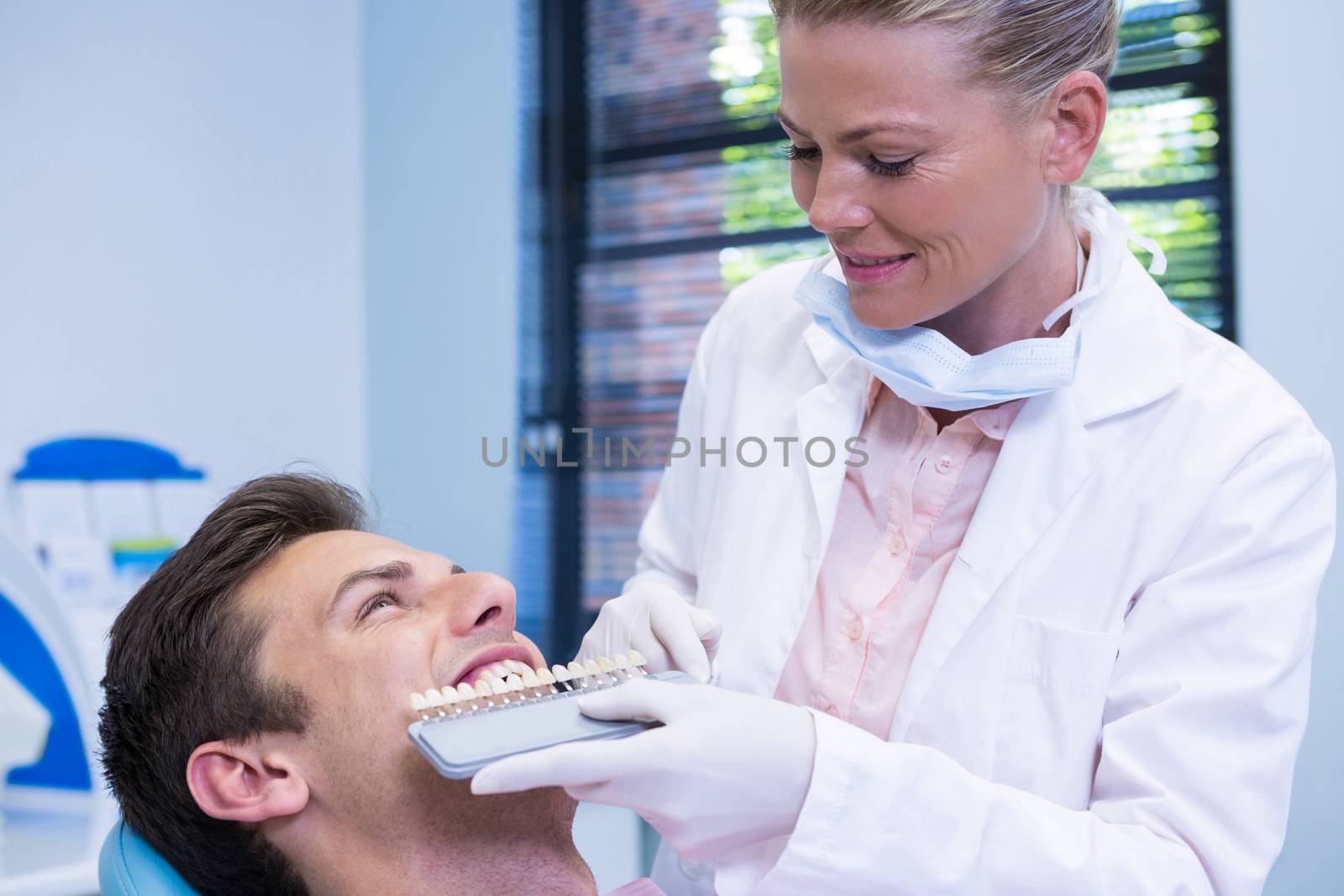 Dentist holding equipment while examining patient at medical clinic by Wavebreakmedia