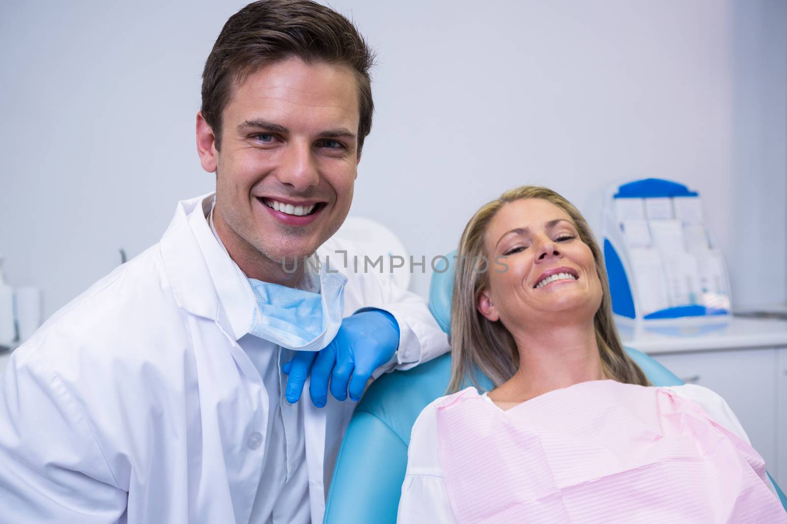 Portrait of smiling patient and dentist sitting on chair at dental clinic