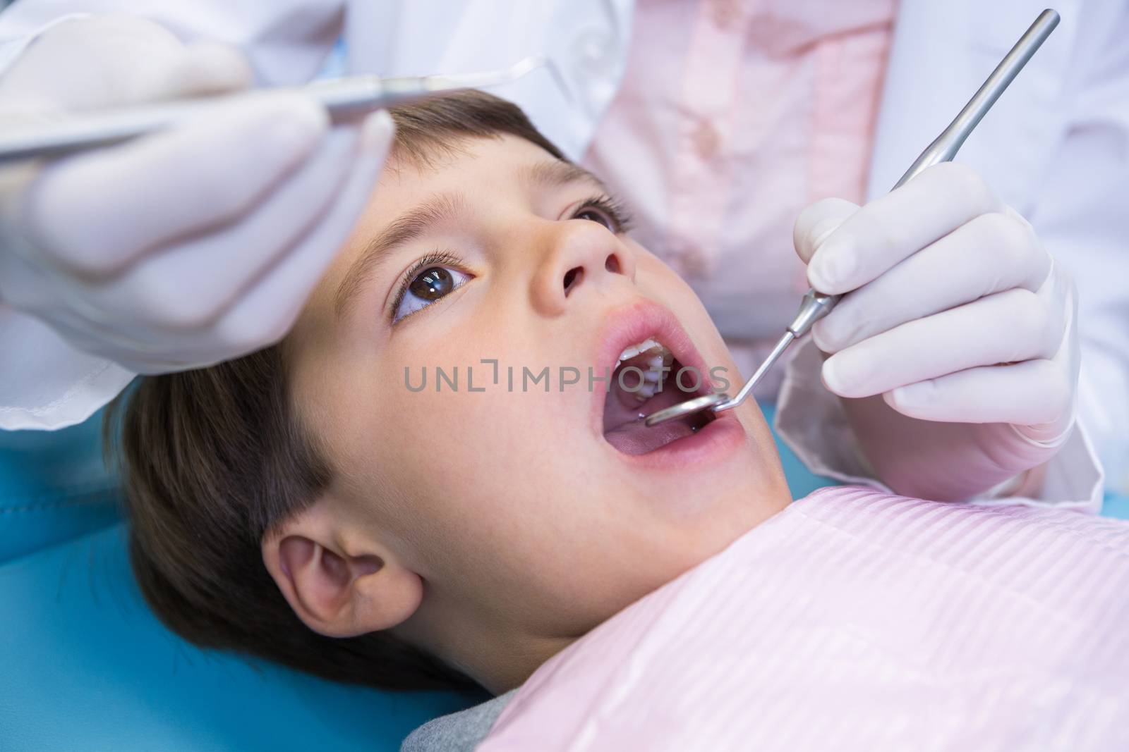 Close up of dentist holding equipment while examining boy by Wavebreakmedia
