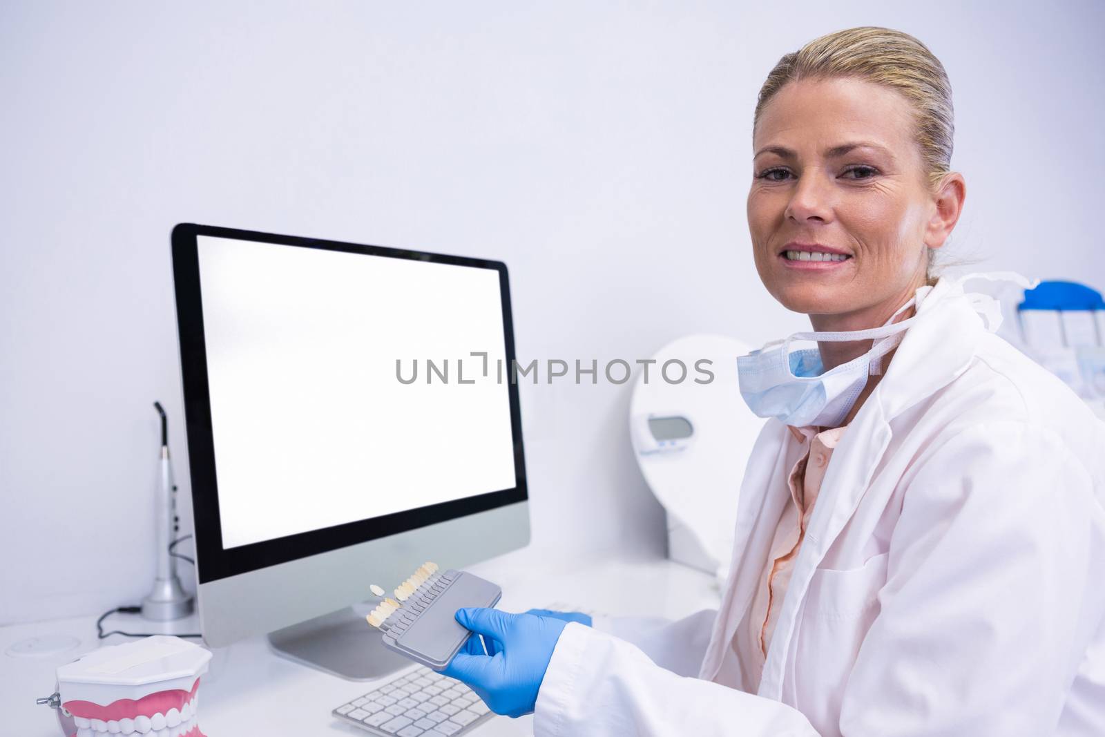 Portrait of dentist working while sitting by computer at clinic