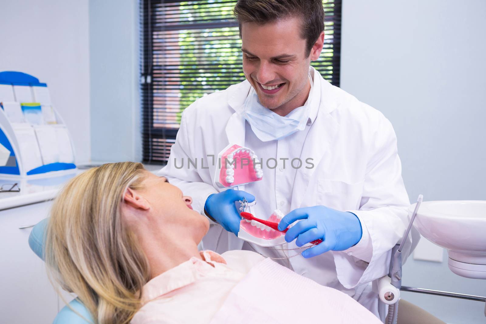 Dentist holding dental mould by woman at clinic by Wavebreakmedia