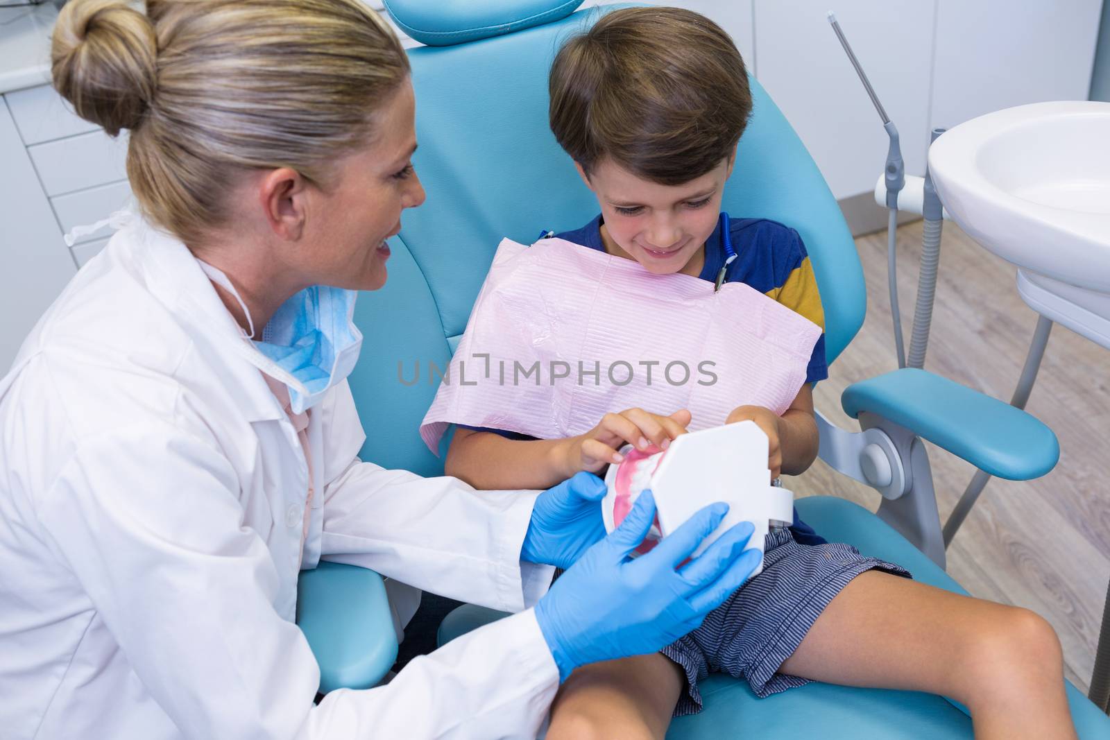 Dentist teaching boy brushing teeth on dentures by Wavebreakmedia