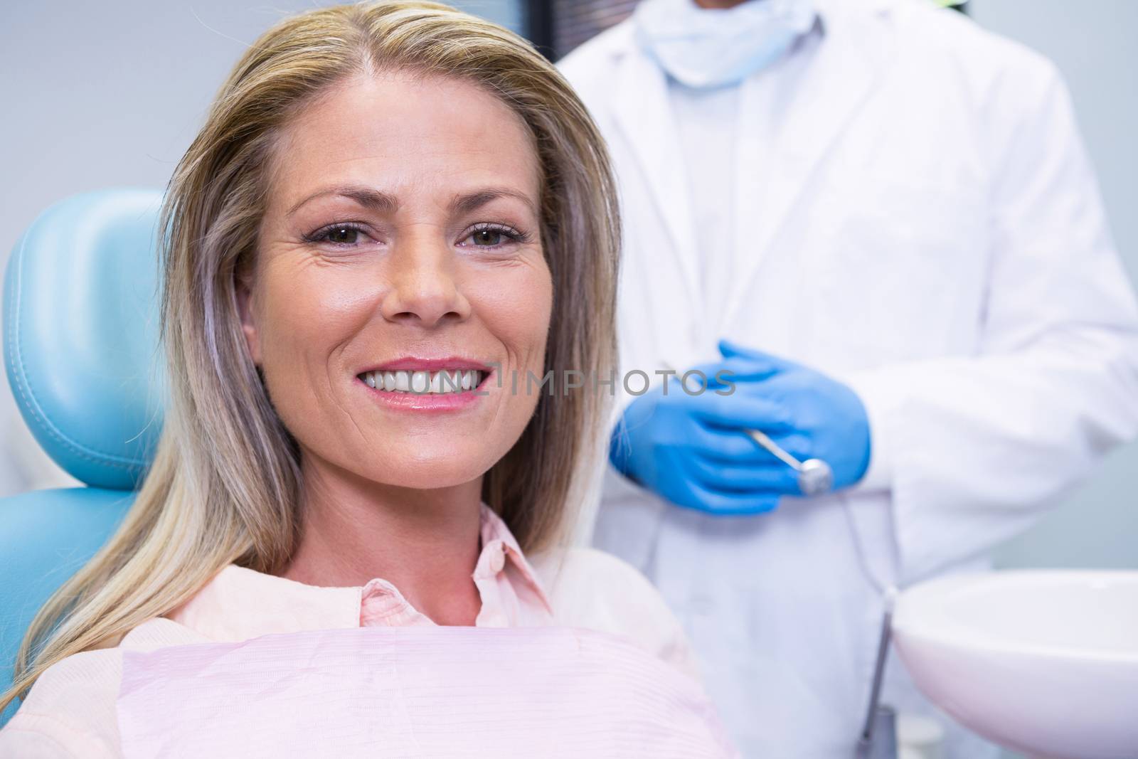 Portrait of patient sitting on chair against dentist at medical clinic