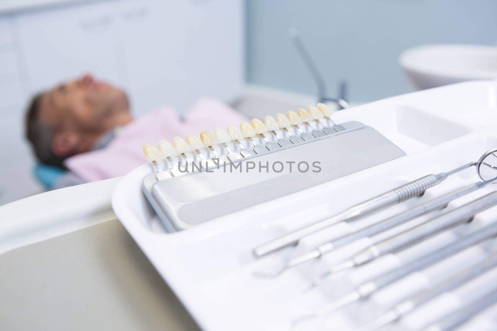 Close-up of medical equipment  on table against man lying on dentist chair by Wavebreakmedia