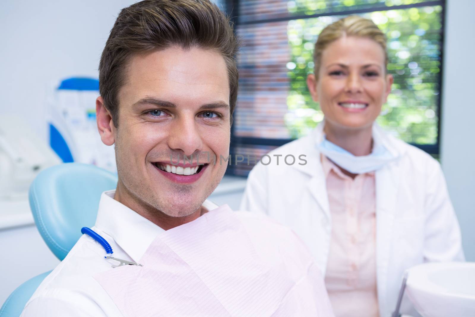 Portrait of smiling man and dentist sitting at dental clinic