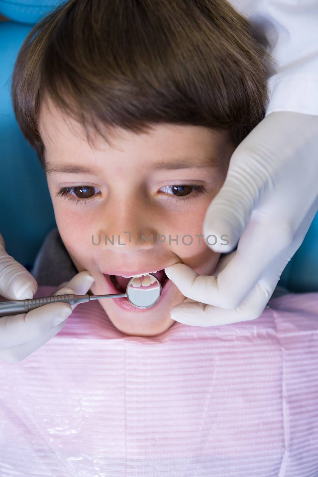 High angle view of dentist holding equipment while examining boy at medical clinic