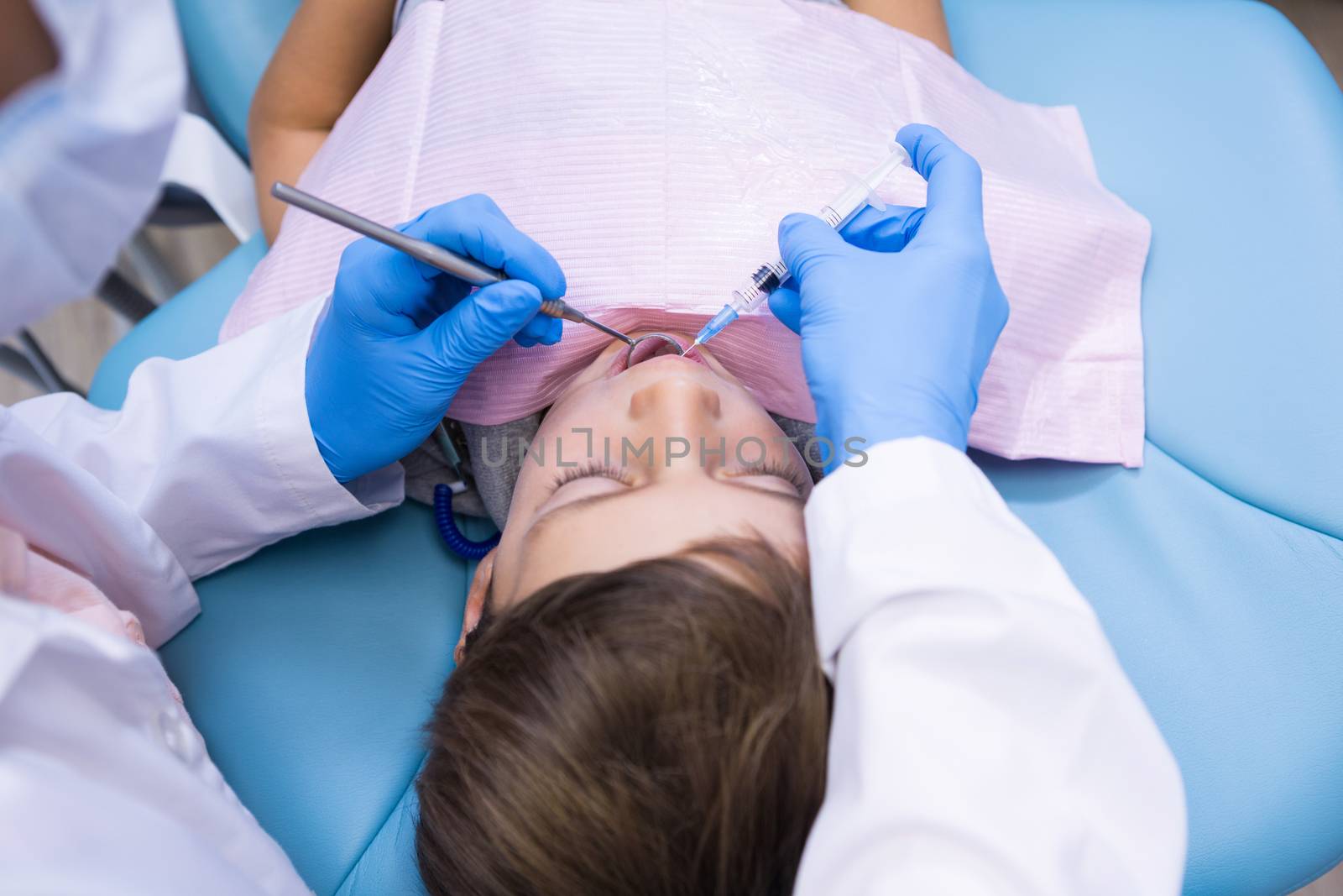 High angle view of dentist holding medical equipment while examining boy at clinic
