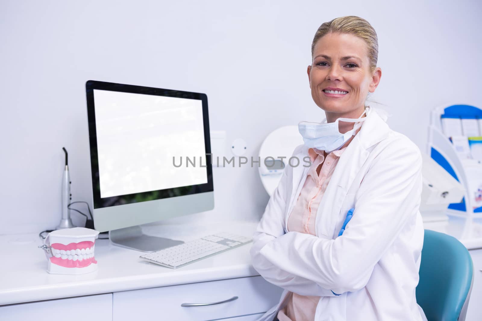 Portrait of smiling dentist working while sitting by computer by Wavebreakmedia