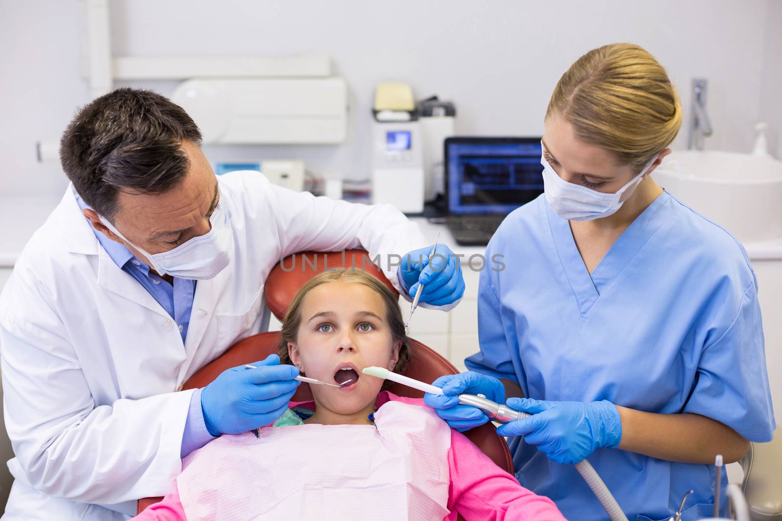 Dentist and nurse examining a young patient with tools in clinic