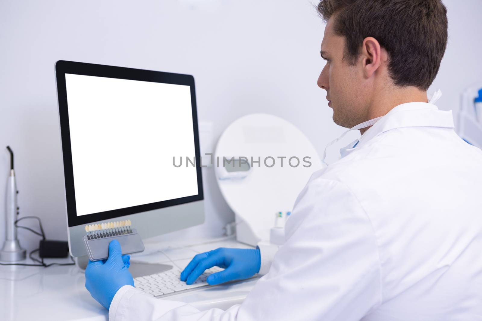 Dentist working on computer against wall at medical clinic