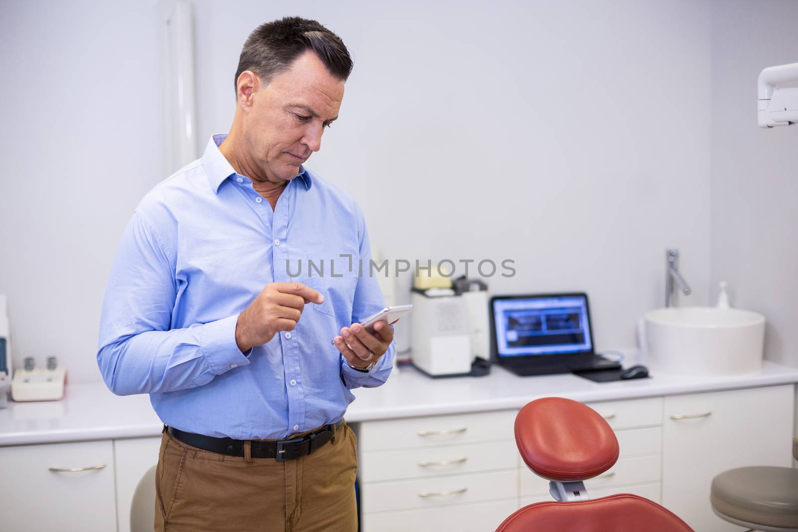 Dentist using mobile phone in clinic