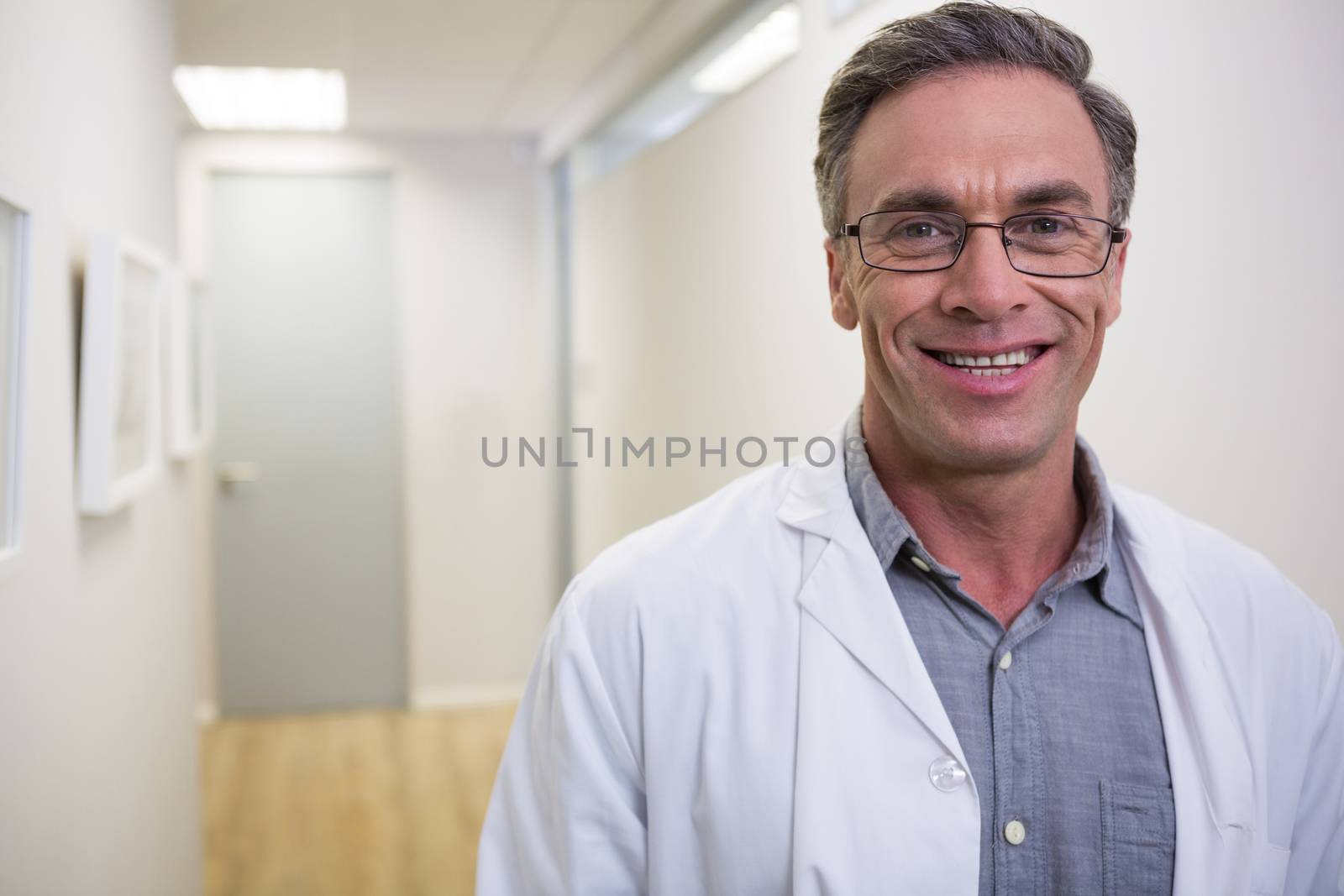 Portrait of smiling dentist standing at lobby in medical clinic