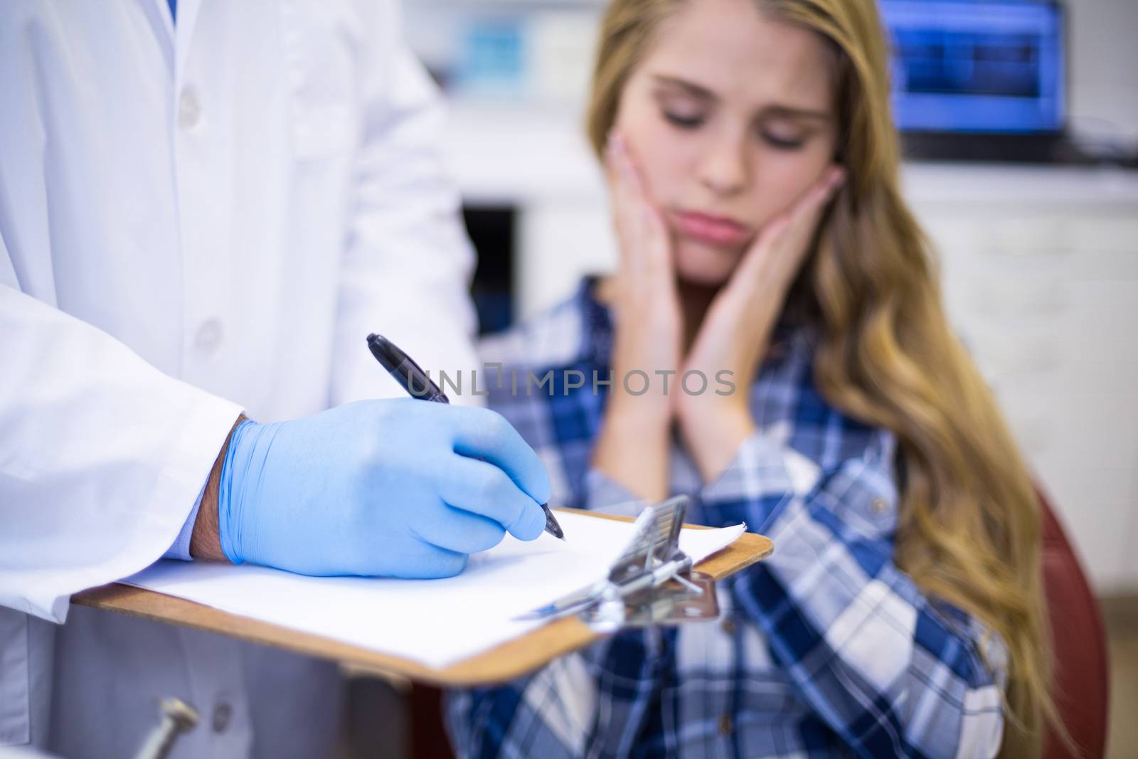 Dentist preparing dental report of female patient in clinic