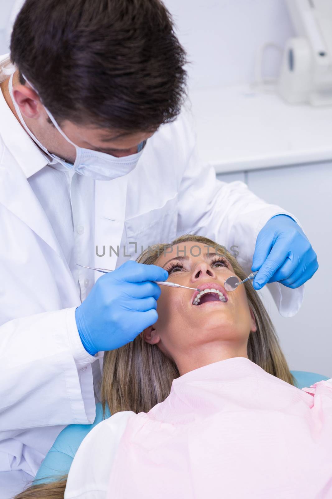 Close up of dentist holding equipment while examining woman by Wavebreakmedia