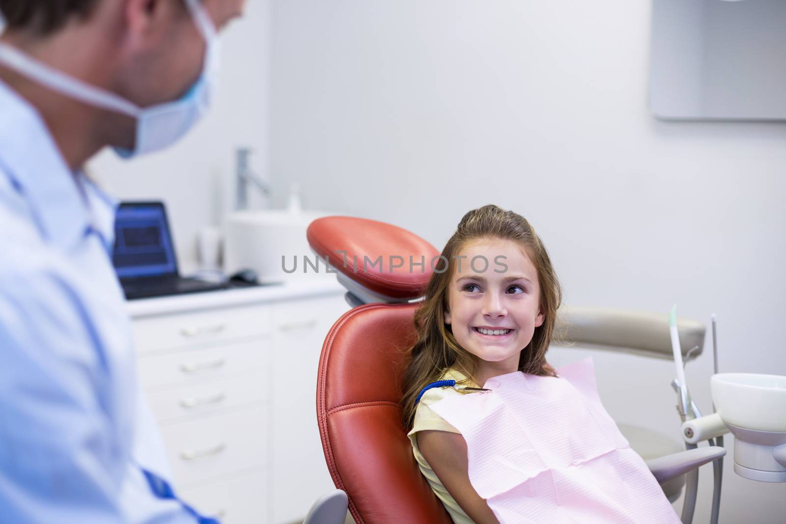 Smiling dentist talking to young patient in dental clinic