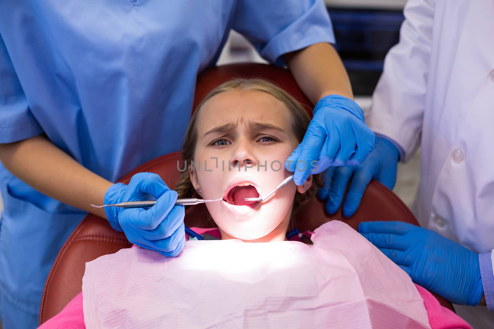 Dentist and nurse examining a young patient with tools by Wavebreakmedia