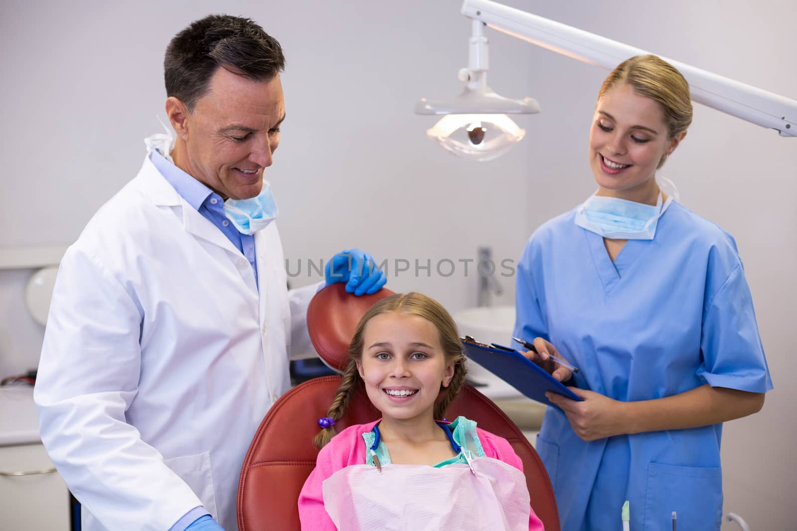 Dentist and female nurse standing beside young patient in clinic