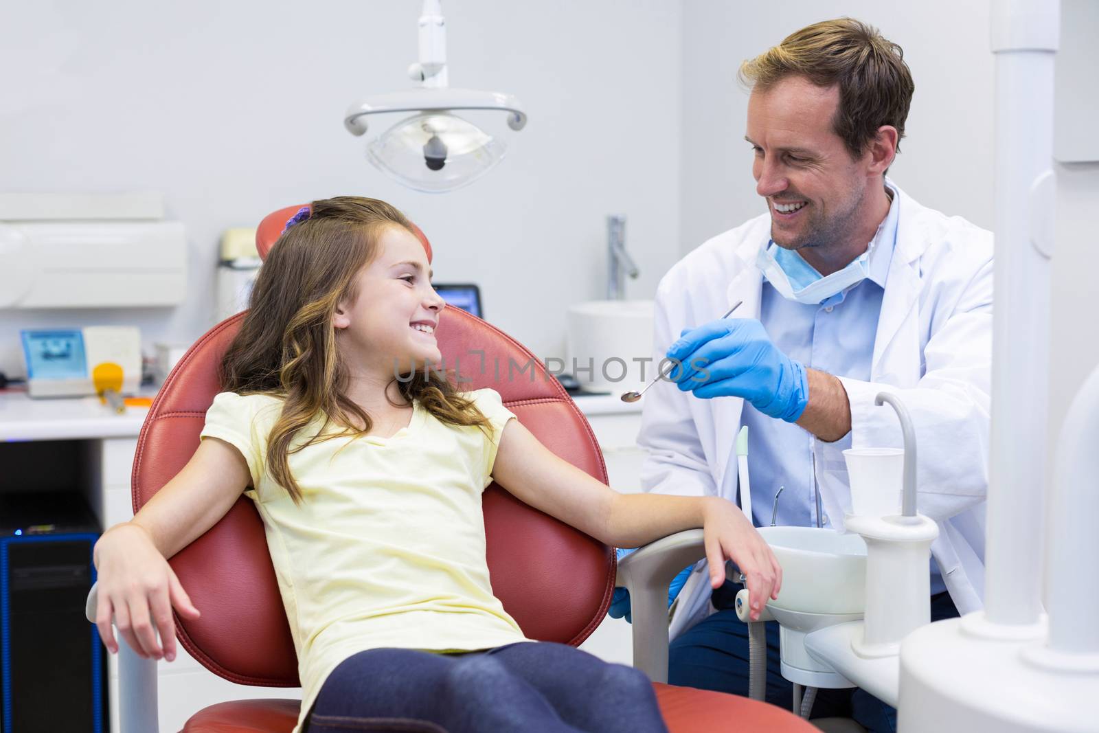 Smiling dentist talking to young patient in dental clinic