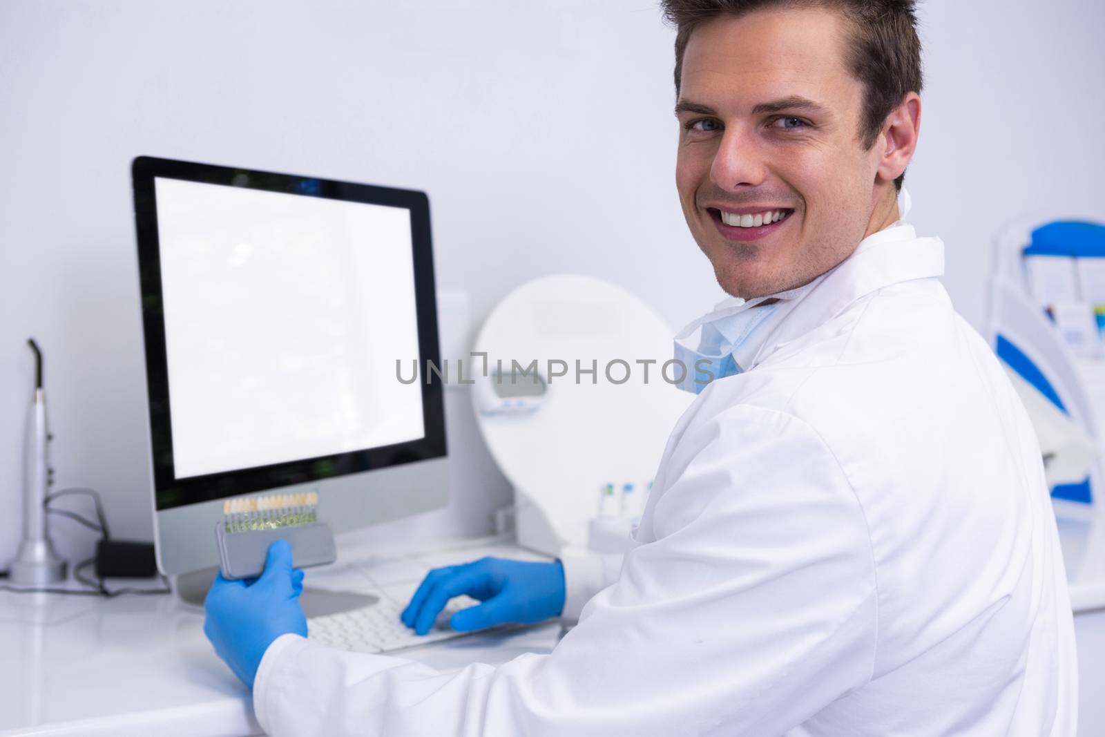 Portrait of dentist working on computer against wall by Wavebreakmedia