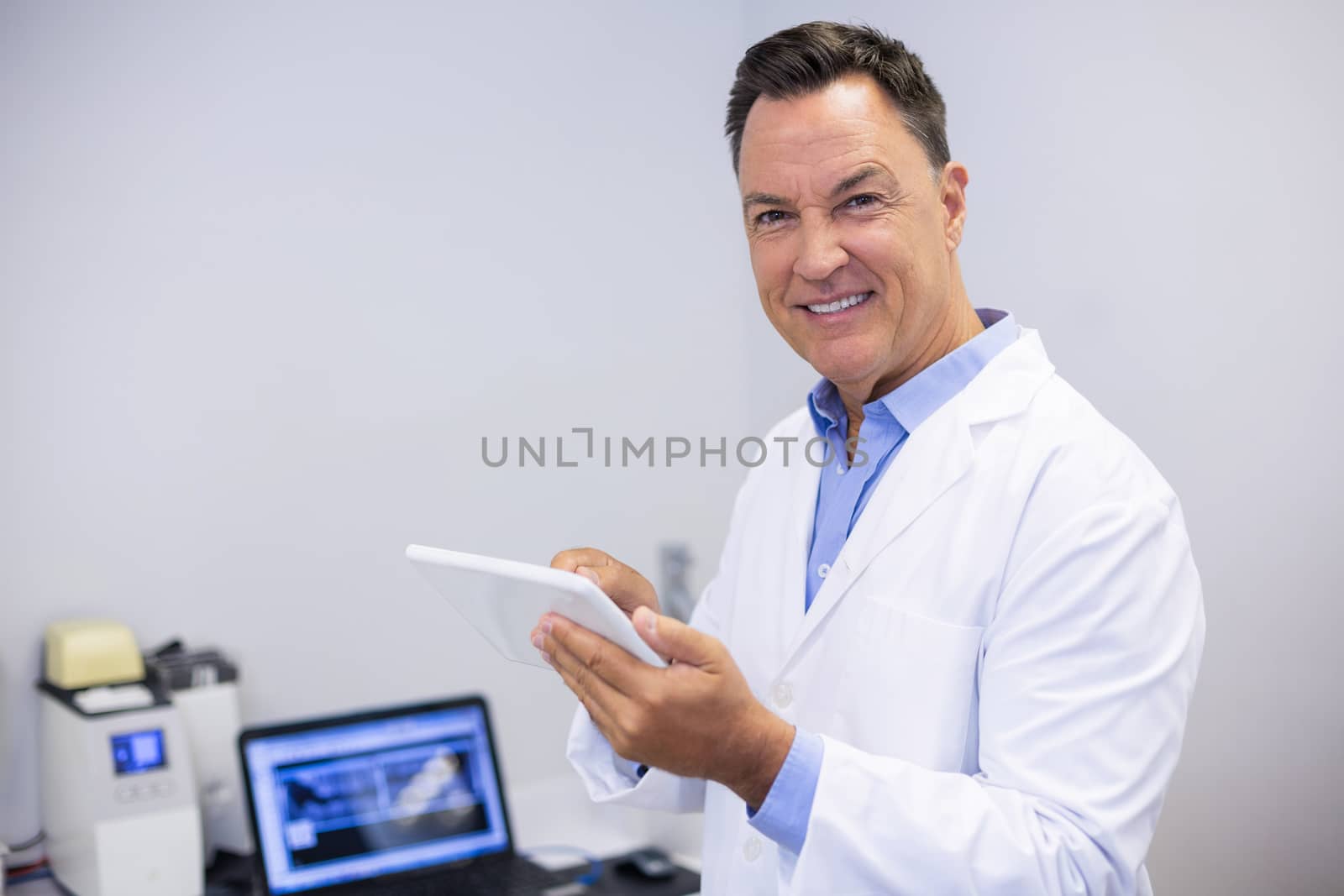 Portrait of happy dentist using digital tablet in clinic