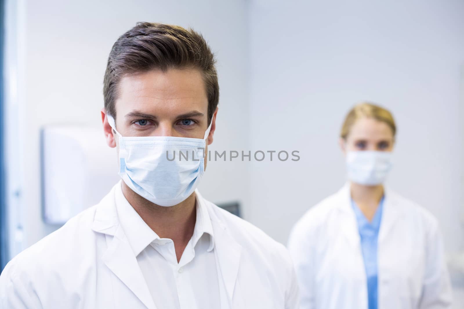 Portrait of dentist wearing surgical mask while his colleague standing in background