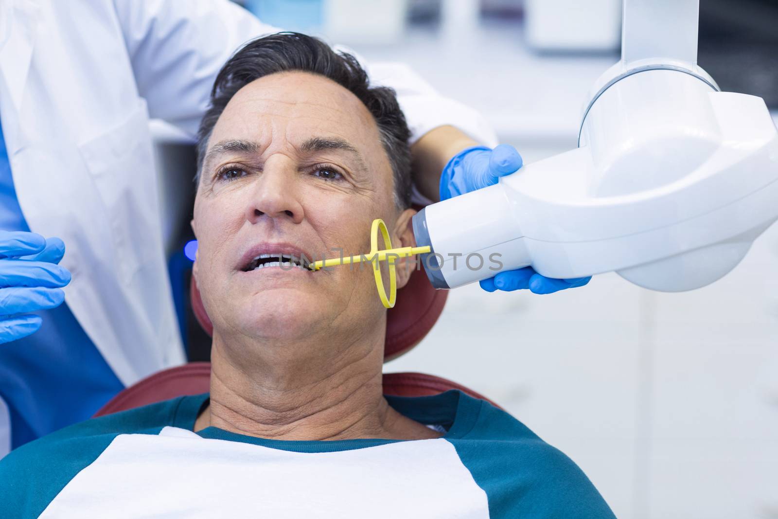 Dentist examining a male patient with tool by Wavebreakmedia