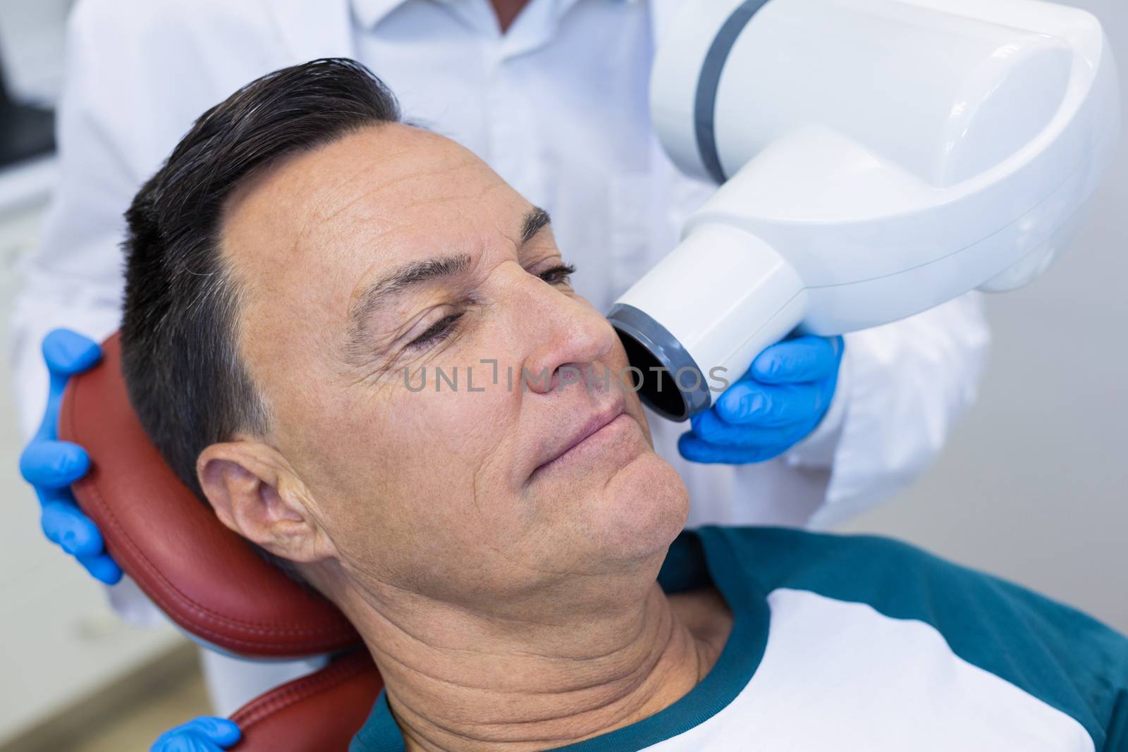 Mid section of dentist examining a male patient with dental tool in clinic