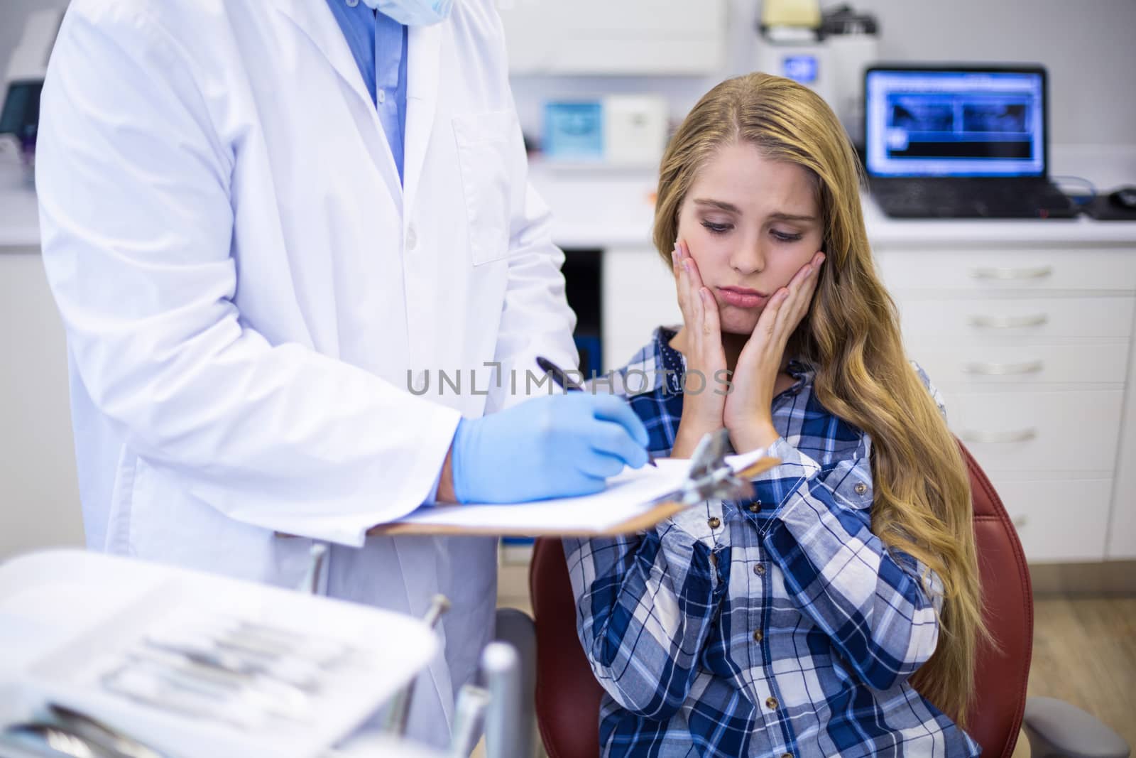 Dentist preparing dental report of female patient in clinic