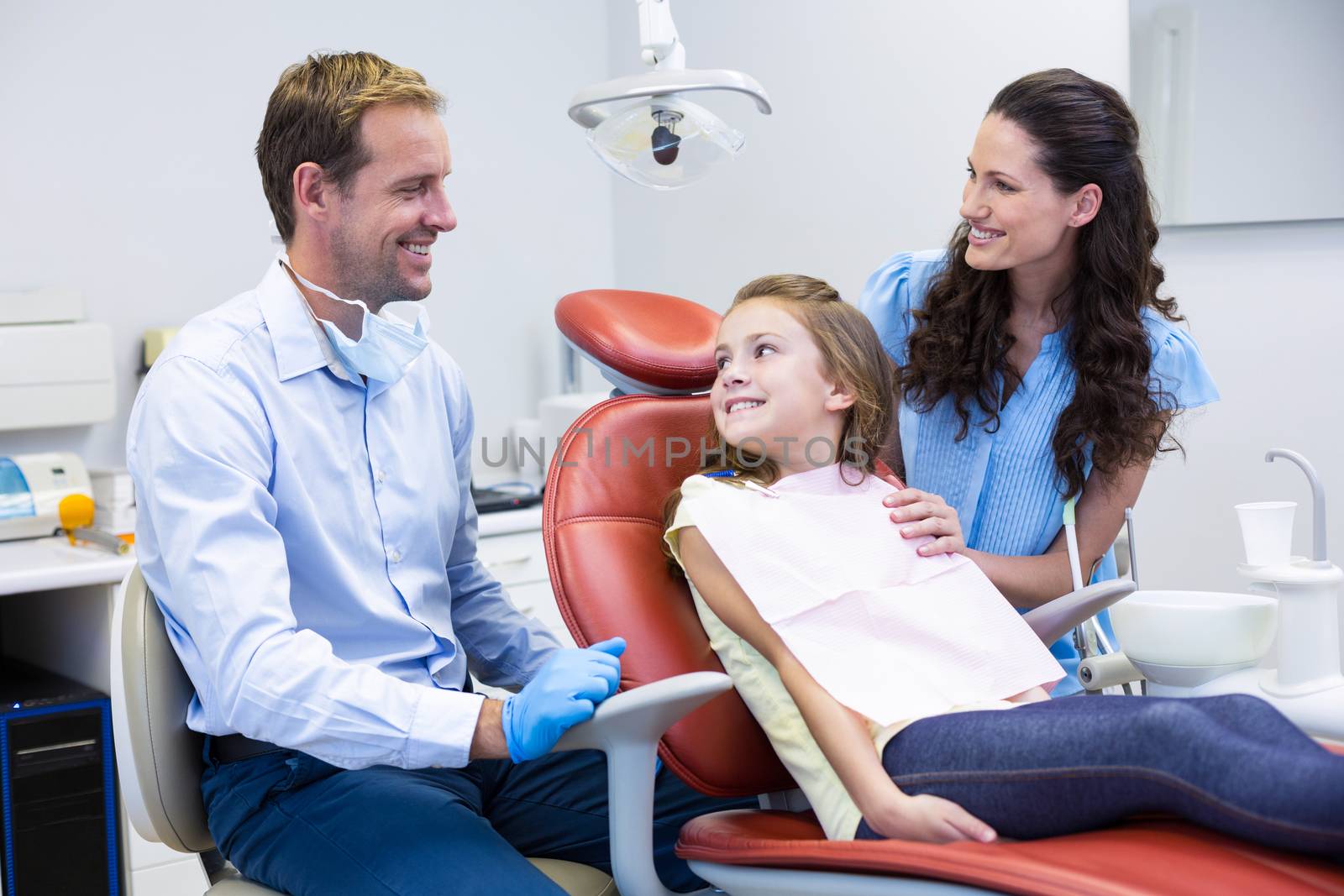 Dentist interacting with mother and daughter while dental examination at dental clinic