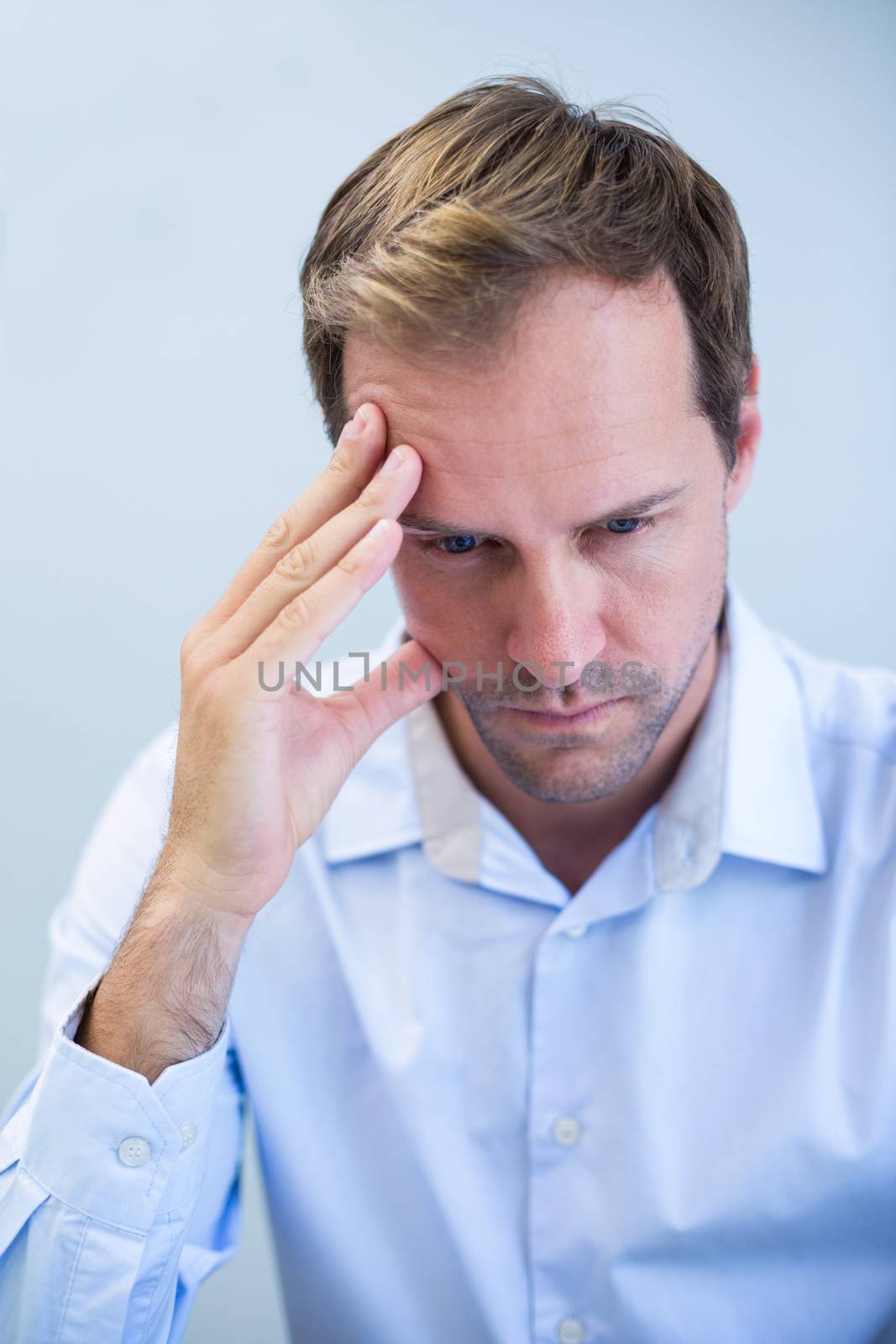 Close-up of tensed dentist sitting with hand on forehead by Wavebreakmedia