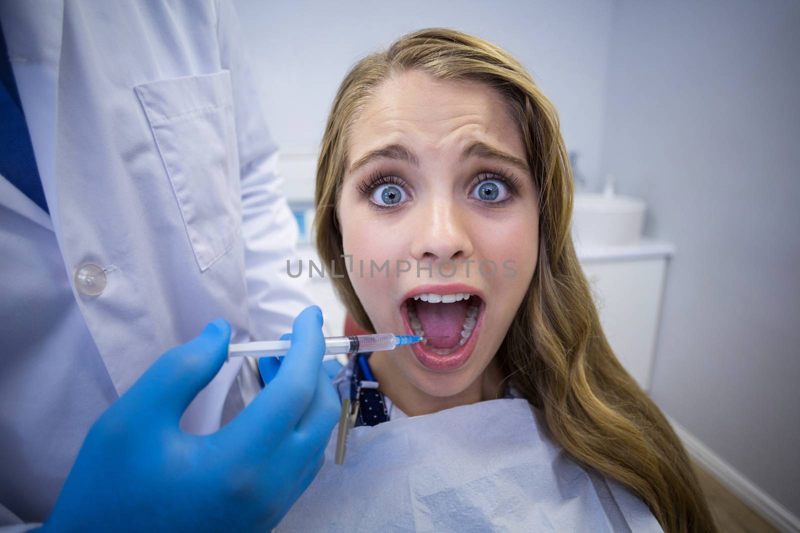 Dentist giving anesthesia to female patient in clinic