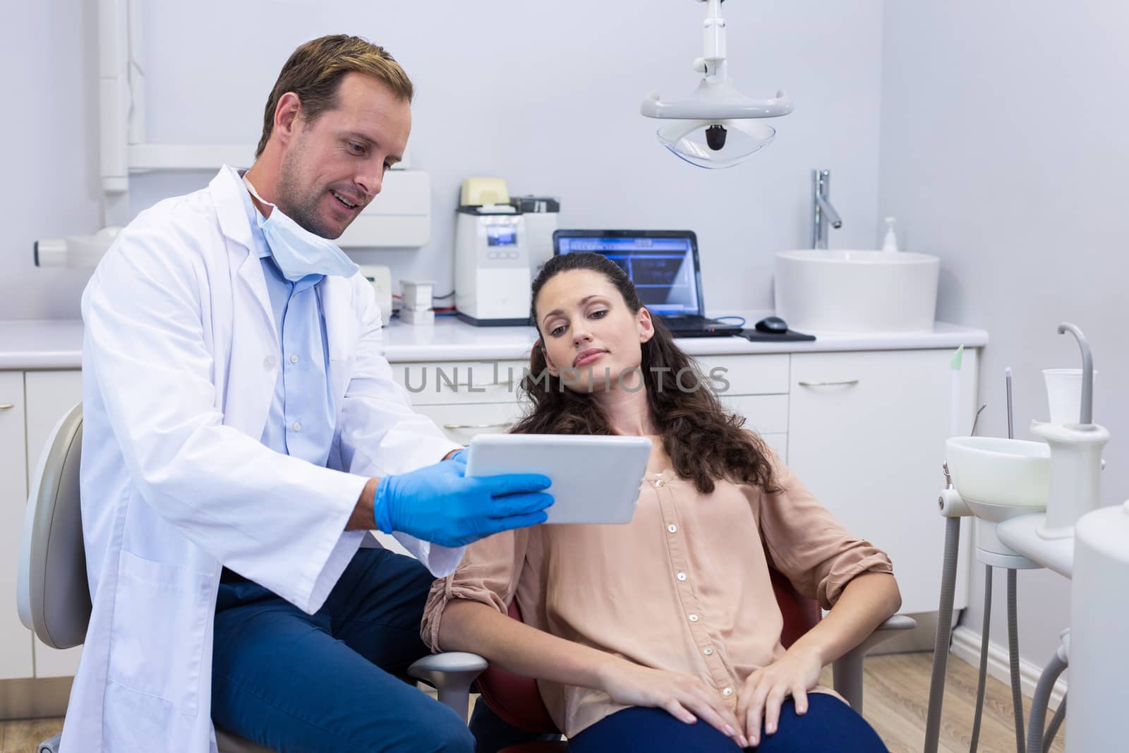 Dentist discussing over digital tablet with female patient by Wavebreakmedia