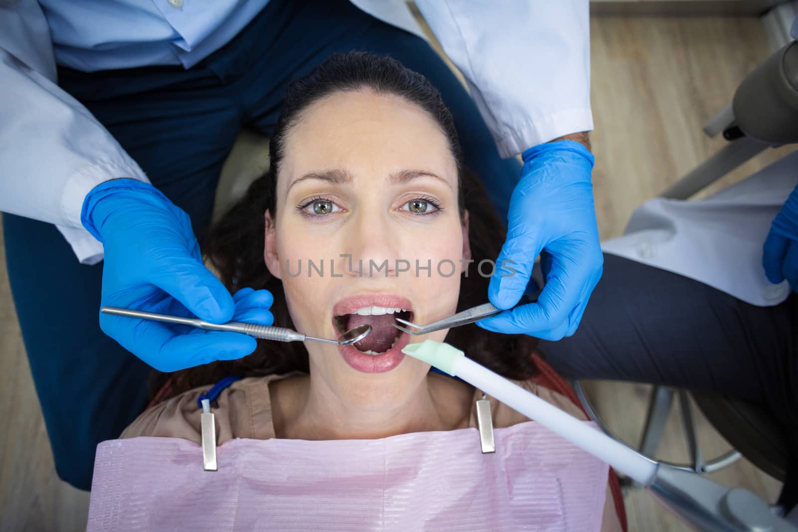 Dentist examining a female patient with tools at dental clinic