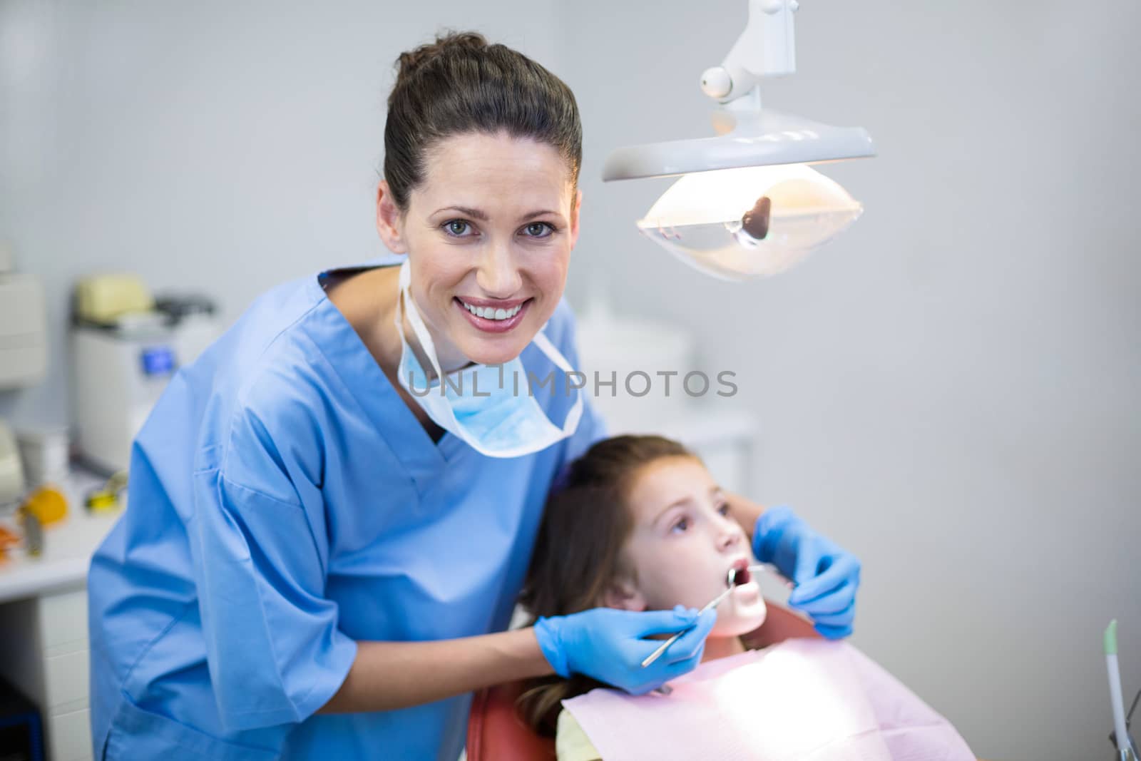 Portrait of dentist examining a young patient with tools in dental clinic
