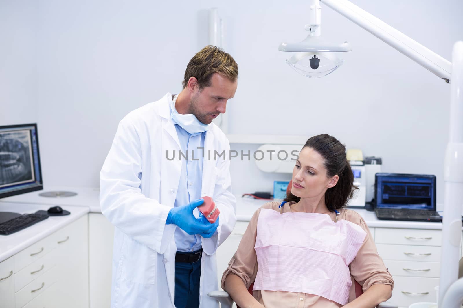 Dentist showing model teeth to patient in dental clinic