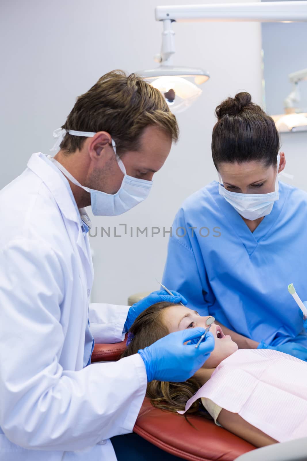 Dentist examining a young patient with tools by Wavebreakmedia