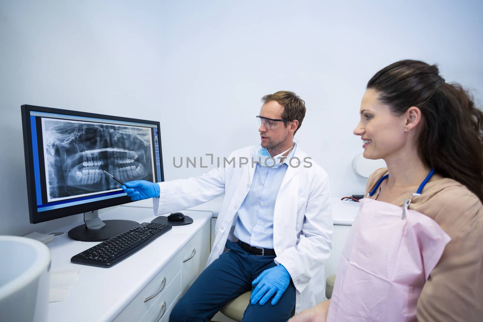 Dentist showing an x-ray of teeth to female patient at dental clinic