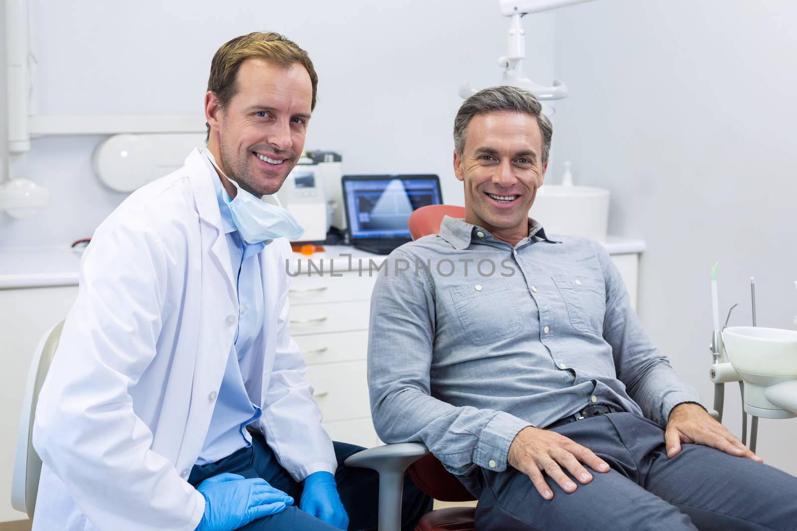 Portrait of smiling dentist and patient in dental clinic