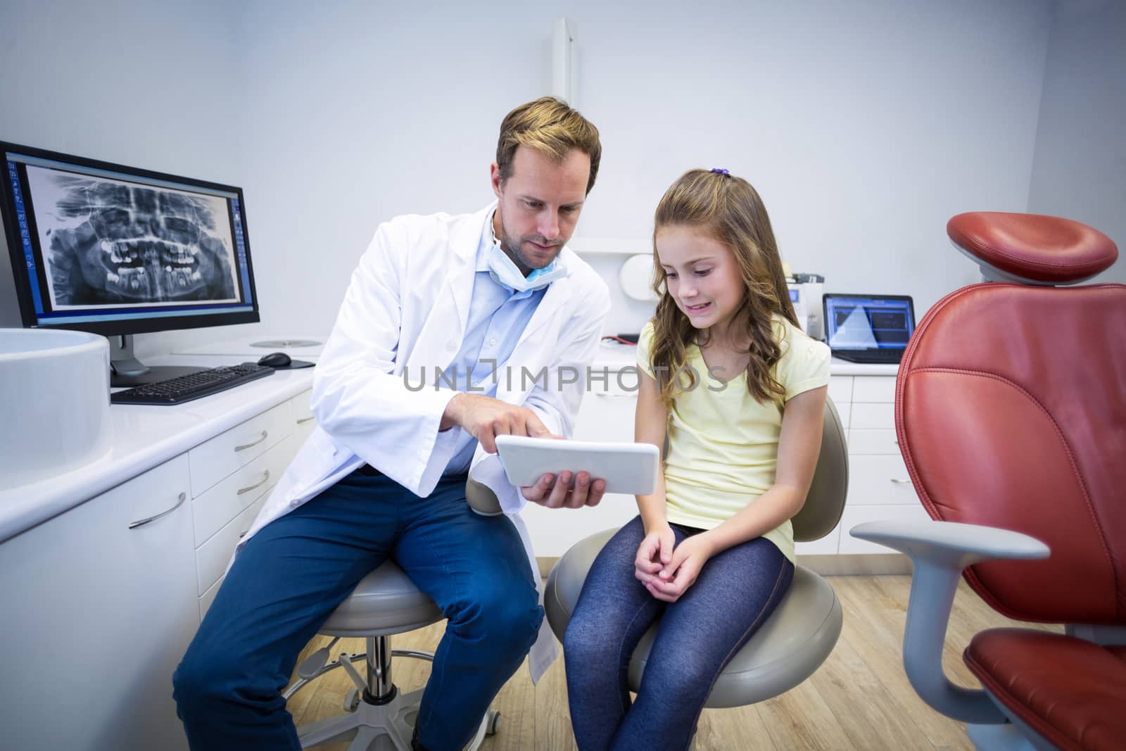 Dentist showing digital tablet to young patient by Wavebreakmedia