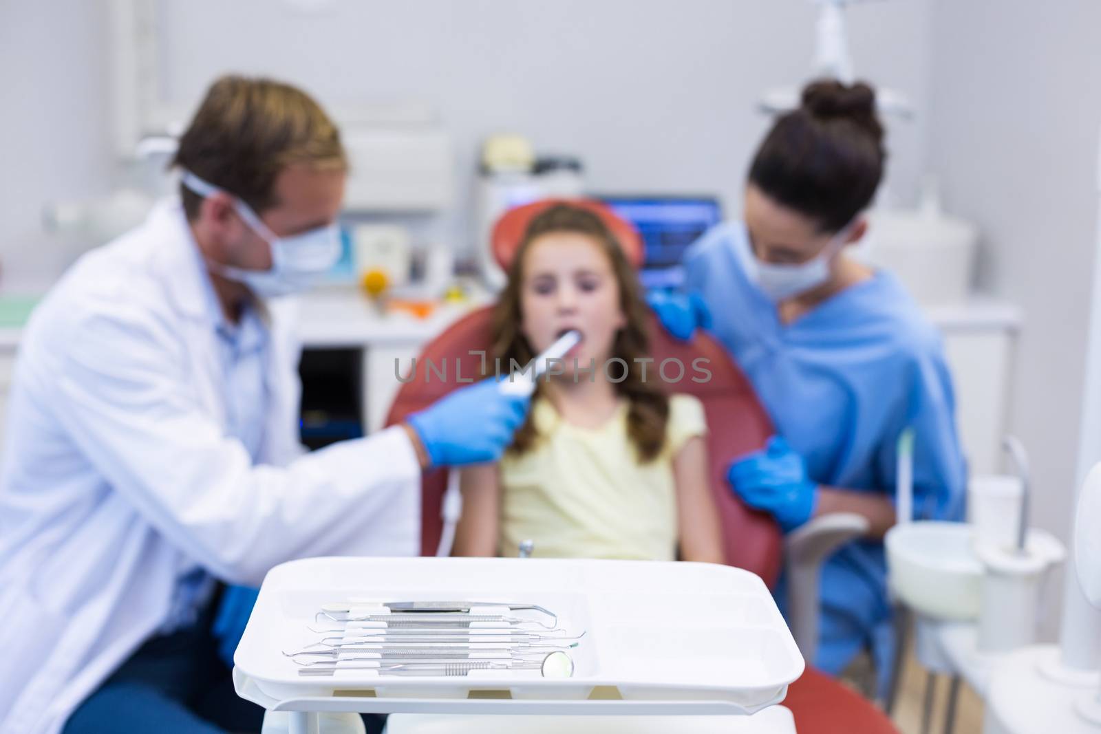 Close-up of dental tool on the clinic and dentist examining a young patient in background