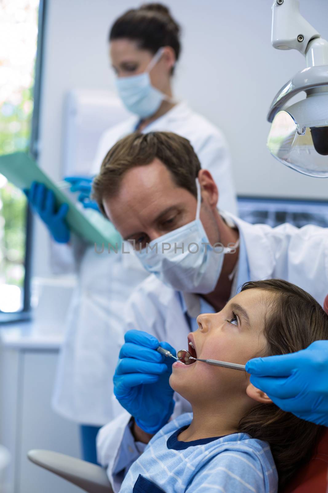 Dentist examining a young patient with tools in dental clinic