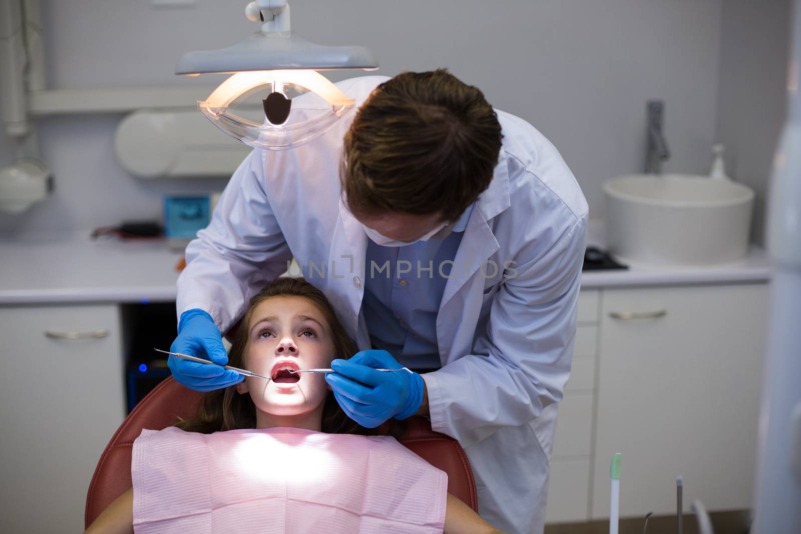 Dentist examining a young patient with tools in dental clinic