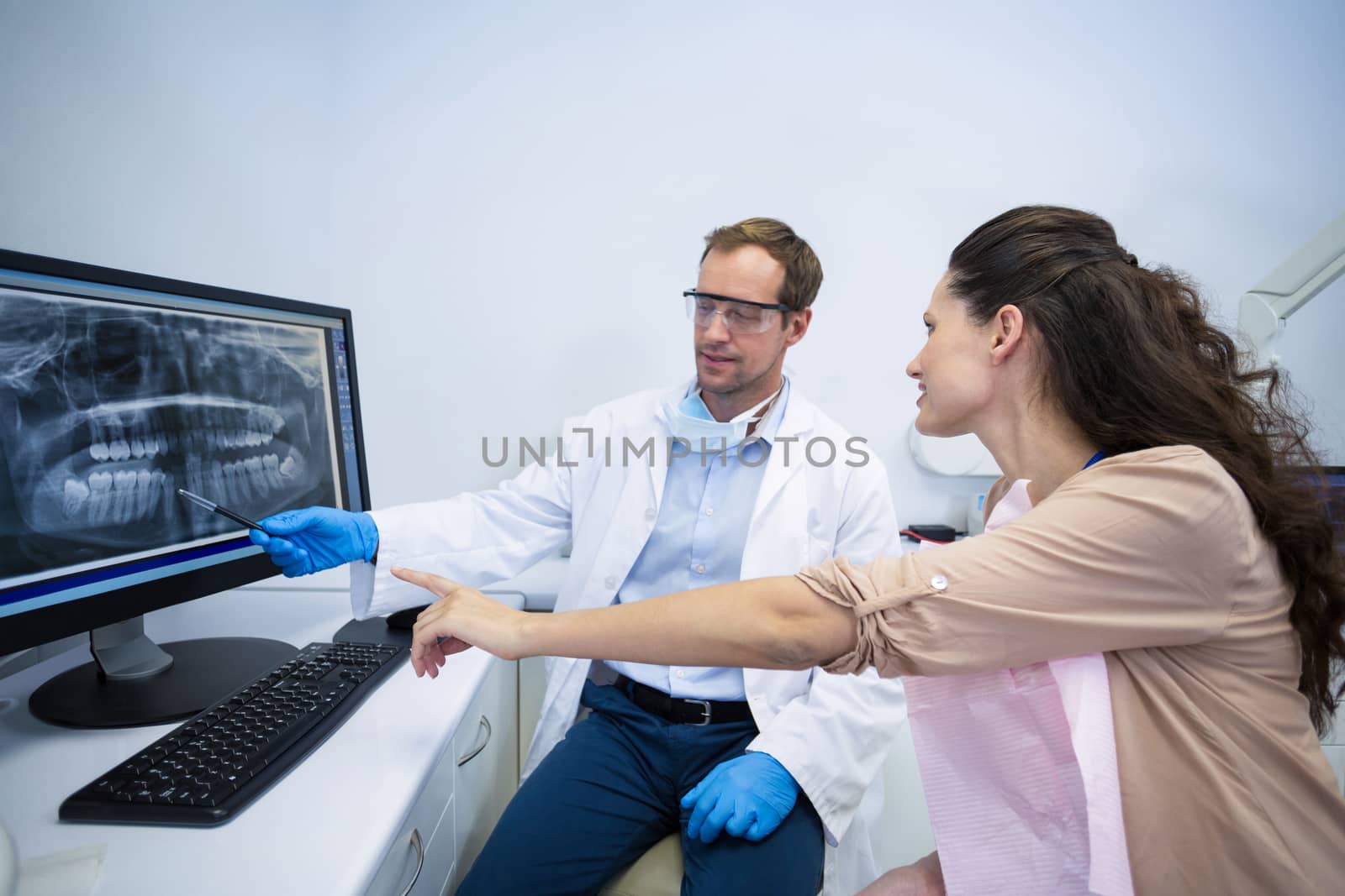 Dentist showing an x-ray of teeth to female patient at dental clinic