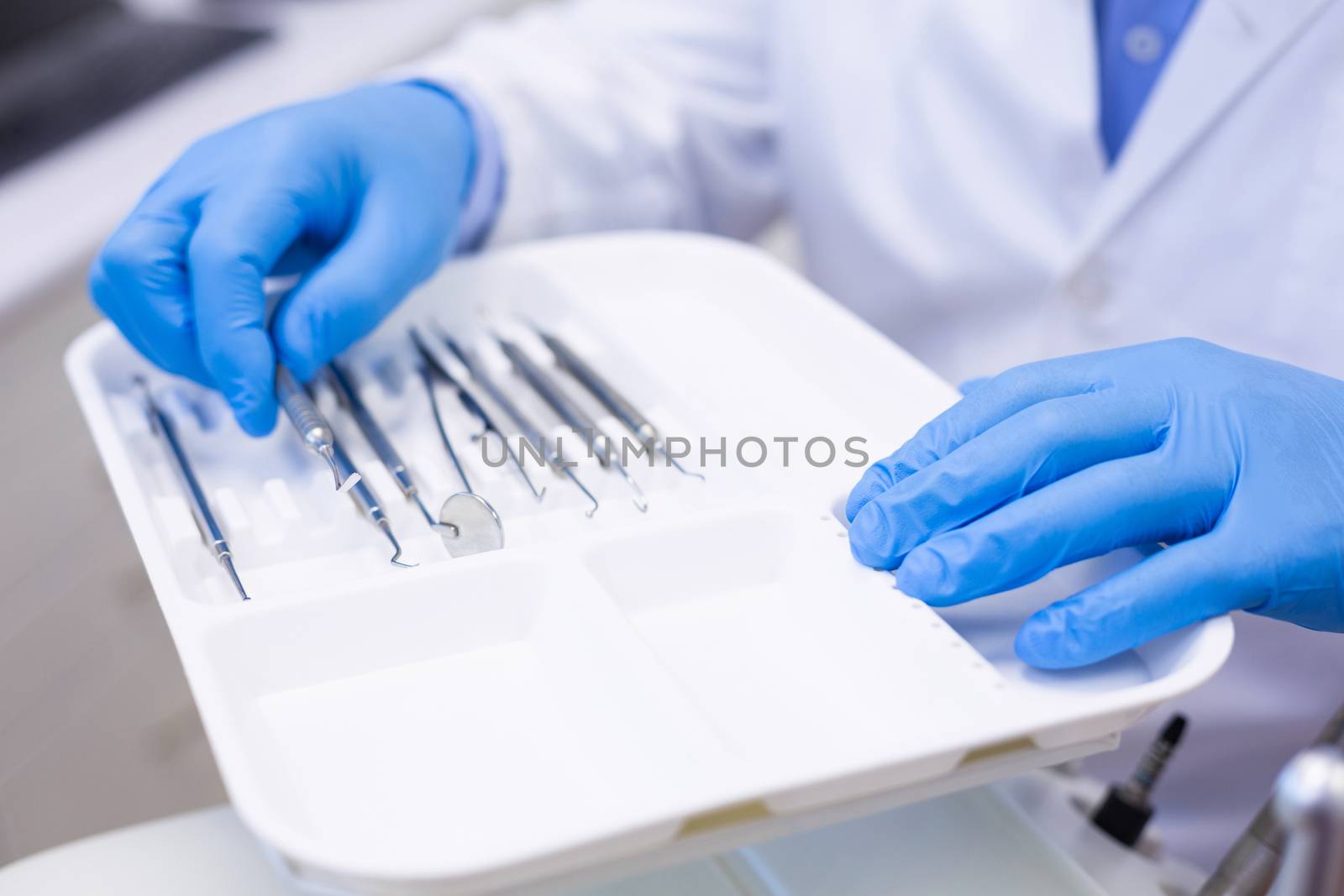 Dentist picking up dental tool at dental clinic