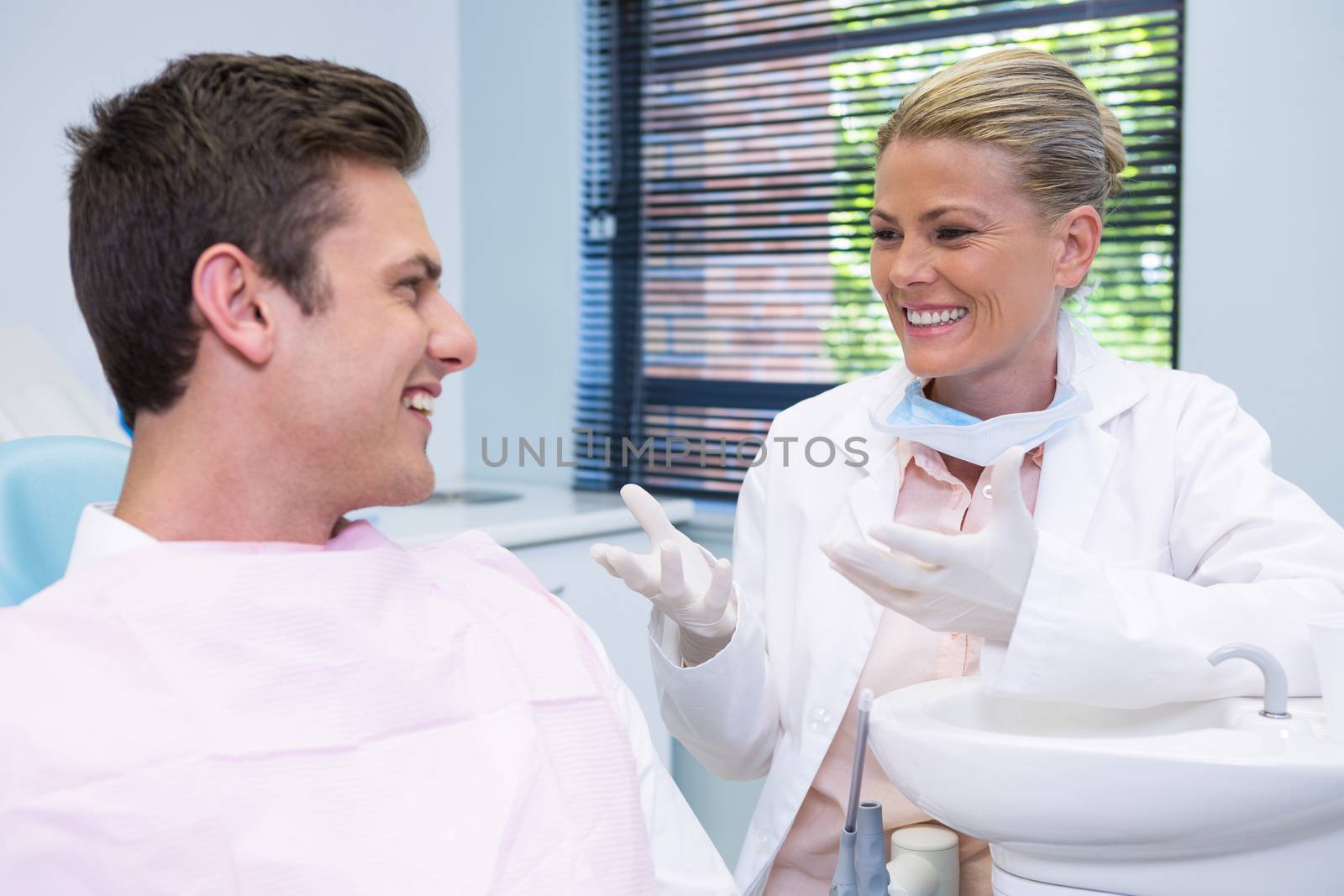 Happy patient discussing with dentist by Wavebreakmedia